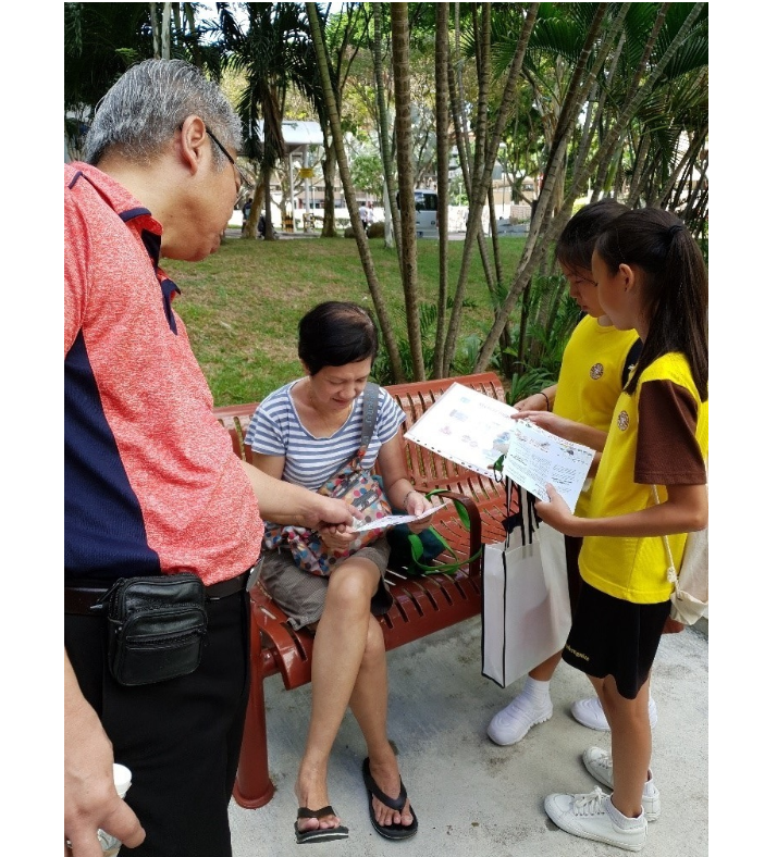 A picture of two primary school brownies girls doing a survey about environmental with a lady in the park accompanied by their male teacher